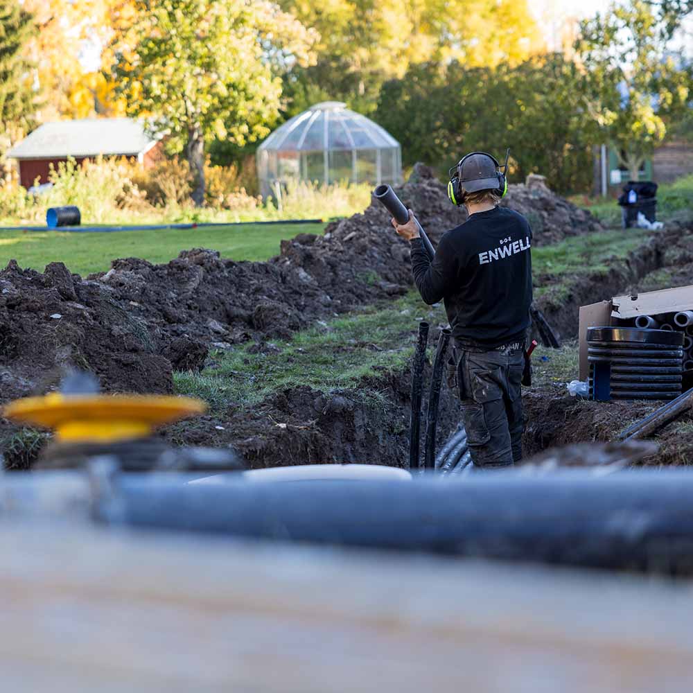 Person som drar kablar i marken vid bergvärmesinstallation